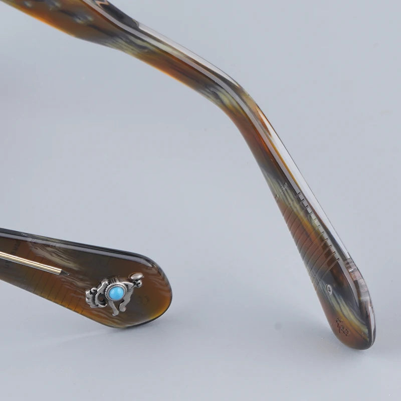 Close-up of a decorative hairpin with tortoiseshell design and turquoise stone on a light gray background