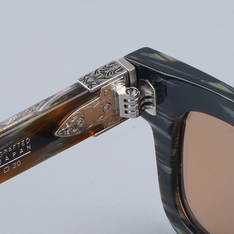 Close-up of a sunglasses frame with decorative metal details on a light gray background